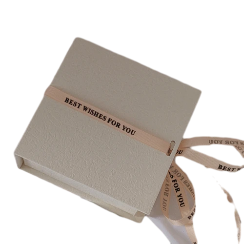 This minimalist flip top magnetic rigid gift box comes in multiple textured exterior colour selections including cream white, deep black and mustard yellow. It is matched with detachable satin ribbon printed with warm wish text for elegant wrapping decoration. The sturdy thick cardboard maintains sharp box shape, and the built in magnet enables smooth opening and tight closure. The interior can hold custom branded fabric drawstring pouches for jewellery, trinkets and cosmetics. Custom surface texture, personalized ribbon printing and bespoke sizing service are supported, well suited for holiday gifts, party favours and brand retail bulk order wholesale.