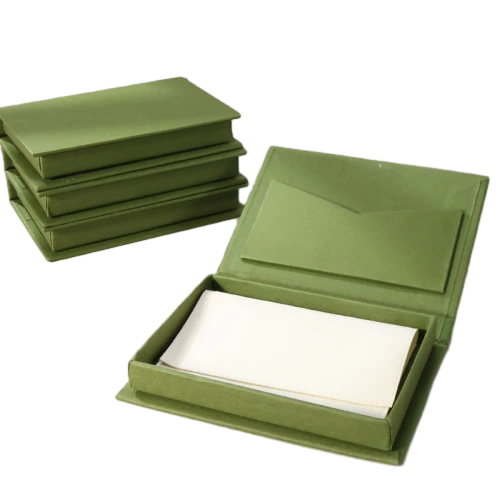 Elegant book shaped flip open custom rigid boxes come in navy blue, olive green, off white and soft pink finishes. The inner lid is fitted with an integrated envelope shaped pocket to hold greeting cards, notes or thank you letters, while the main cavity can store pearl necklaces, bracelets and fine jewellery. Premium thick hard paper construction keeps the box stiff and distortion free, and hot stamping gold foil floral logos, personalised branding and custom sized modifications are supported. It works perfectly for high end jewellery storage, wedding day invitation packing, souvenir gifts and wholesale custom made orders.