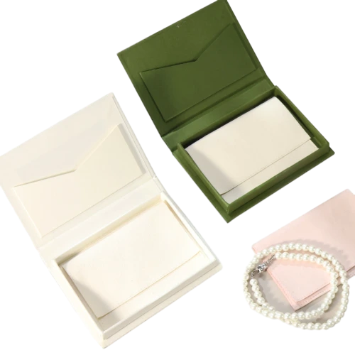 Elegant book shaped flip open custom rigid boxes come in navy blue, olive green, off white and soft pink finishes. The inner lid is fitted with an integrated envelope shaped pocket to hold greeting cards, notes or thank you letters, while the main cavity can store pearl necklaces, bracelets and fine jewellery. Premium thick hard paper construction keeps the box stiff and distortion free, and hot stamping gold foil floral logos, personalised branding and custom sized modifications are supported. It works perfectly for high end jewellery storage, wedding day invitation packing, souvenir gifts and wholesale custom made orders.