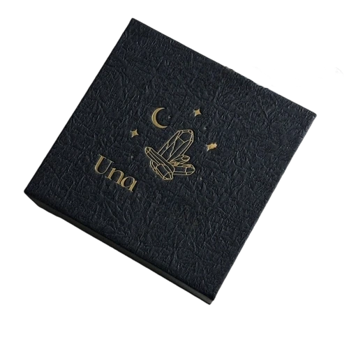 This premium square custom rigid box is built with thick hardboard and wrapped in distinctive crinkled textured black paper. Shiny gold foil stamping is available for brand name crystal moon and star artwork on the top surface. Magnetic flip lid provides smooth opening and secure closure. You can add velvet or foam inner inserts to safely store crystals pendants earrings and other spiritual jewelry items. Its sturdy hard shell offers solid protection during transit and retail display. It is an excellent luxury packaging choice for crystal jewelry brands and large volume wholesale orders.