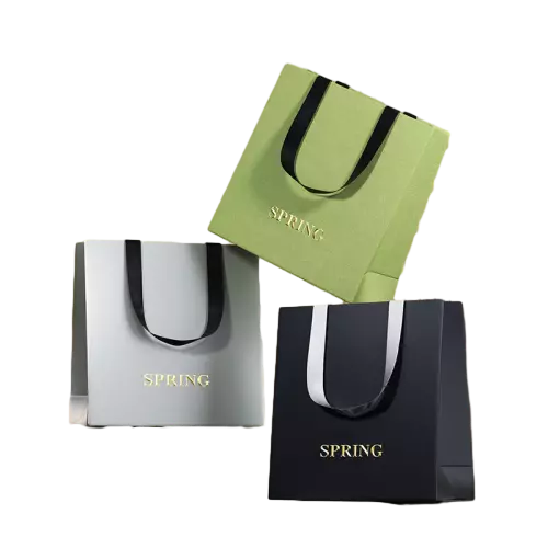 These fashionable special craft paper bags are available in multiple elegant matte color options. Exquisite hot gold foil letter logo adds high end texture to the bag surface. Soft satin ribbon handles provide comfortable grip and strong bearing force. The stable square bottom structure keeps the bag standing firmly on flat surfaces. Thick premium paper material resists deformation during daily use. Customers can customize foil stamping patterns brand names and slogans to match brand styles. These stylish paper bags are excellent packaging solutions for clothing cosmetics small gifts and boutique retail sales. Wholesale bulk orders are welcomed.