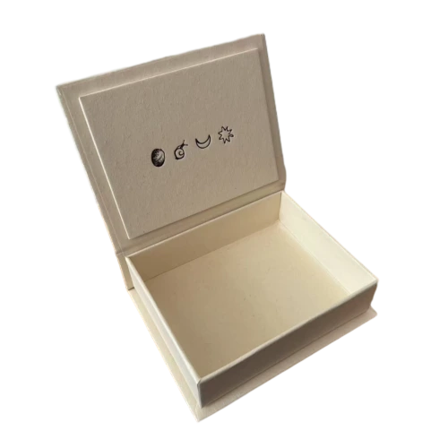 This minimalist creamtoned custom rigid box is built with thick durable hardboard and wrapped in fine textured natural paper. Elegant sun moon and planet celestial icons are hot stamped on the inner lid for subtle artistic branding. Hidden magnetic closure ensures easy opening and secure fit. The clean spacious inner cavity can hold rings earrings pendants bracelets and other small fine jewelry pieces. You can customize embossed debossed or foil stamped logos symbols and text on inner or outer surfaces. Its solid rigid construction protects delicate accessories well during transit and retail shelf display. It is a simple sophisticated packaging selection for jewelry brands and large volume wholesale orders.