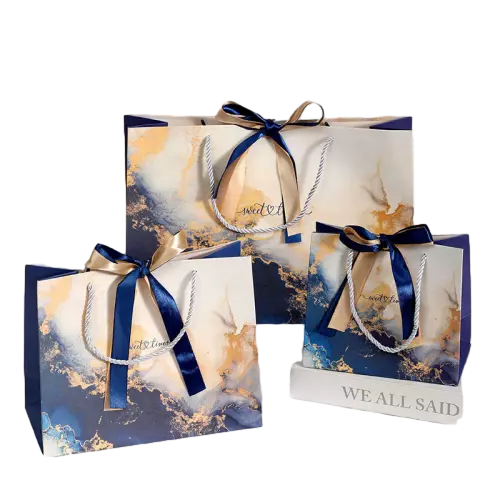 These luxurious special craft paper bags feature stunning ink wash marble patterns blended with delicate golden foil speckles. Each bag is fitted with durable twisted white paper rope handle and decorated with an elegant dualcolor satin ribbon bow. Multiple complete sizes are available to satisfy different gift packaging demands. Thick high quality coated paper provides great rigidity and keeps the bag standing steadily. You are allowed to customize printed logos slogan texts and artwork patterns on the bag surface. These beautiful gift bags are perfectly suited for wedding favors birthday surprises holiday giveaways and high end boutique product packaging. Wholesale bulk orders are welcomed.