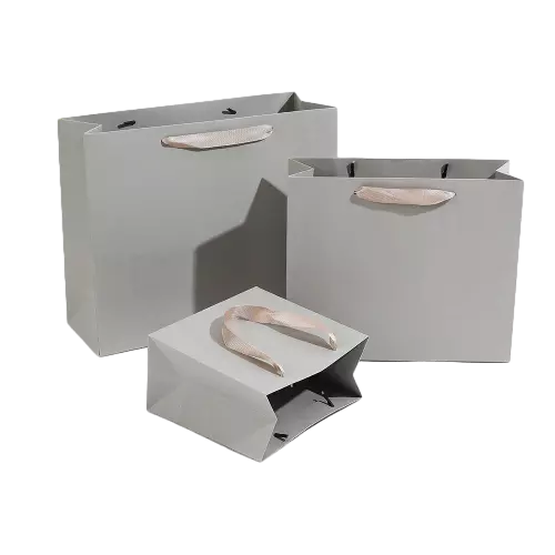 These blank neutral paper gift bags are manufactured from premium thick paper with smooth matte light grey surface. Elegant champagne satin ribbon handles bring soft luxurious touch and reliable load bearing performance. Three different sizes are available to hold jewelry cosmetics clothing and various retail products. Heavy duty paper structure enables each bag to stay upright steadily. The clean blank exterior allows you to add custom printed logo brand slogan and decorative patterns according to your branding needs. These versatile grey tote bags are ideal packaging solutions for fashion shops beauty boutiques and general occasion gift delivery. Wholesale bulk orders are welcomed.