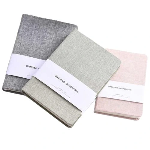 This premium hard cover notebook adopts textured linen fabric outer shell with delicate woven texture, rounded durable book corners and attached silk bookmark ribbon. The thick cream shade lined writing paper delivers soft handwriting friendly performance and prevents ink through. Four muted tone fabric covers are available. Equipped with decorative waistband paper label, the notebook features elegant minimalist styling, well suited for business office records, daily planners, student study notes and customized corporate gift wholesale orders.
