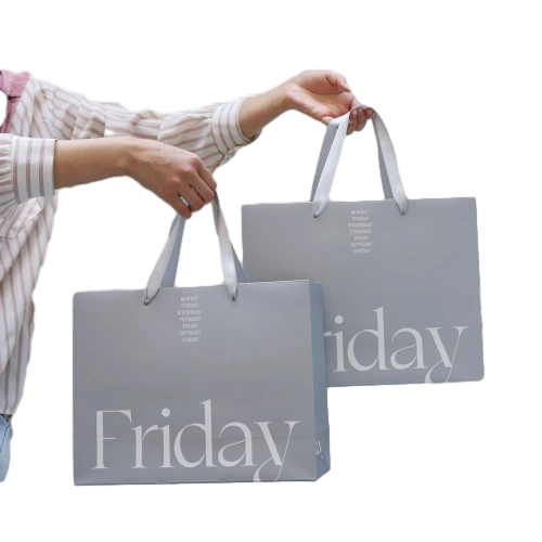 Special Craft Paper Bags adopt elegant misty grey surface printed with big white Friday letter and stacked weekly text above. Matching white ribbon handles are smooth and sturdy for comfortable carrying. Thick premium craft paper keeps the bag upright and maintains neat shape. The low key grey tone with fresh typography creates minimalist trendy style for brand retail and gift delivery. We support custom bag size base color printed text and brand logo. These paper bags fit fashion boutique shopping cosmetic packaging birthday gifts and holiday gift sets.