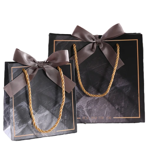 Special Craft Paper Bags adopt stylish black marble printed paper decorated with delicate gold border and best wish text. Sturdy gold twisted rope handle brings great load bearing capacity, matched with elegant brown satin bow decoration. Thick premium craft paper keeps the bag rigid and holds shape steadily. Classic dark marble texture delivers luxury mature aesthetic suitable for various gift scenarios. We support custom bag size printed pattern logo and surface craft. These paper bags work well for wine packaging cosmetic gifts birthday presents anniversary and holiday gift sets.