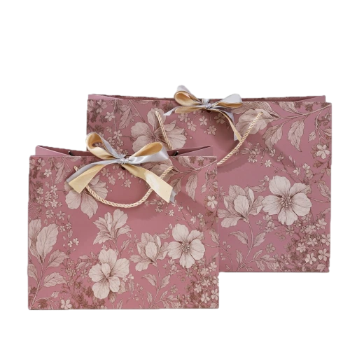 Special Craft Paper Bags feature elegant dusty rose surface fully covered with delicate monochrome vintage floral artwork. Gold twisted rope handles are sturdy and decorative. Two tone satin bows in gold and grey are tied at handle base to enhance romantic gift atmosphere. Thick premium craft paper keeps the bag upright and maintains nice shape. Two sizes available to suit different present packing needs. We support custom bag size floral artwork bow style and brand logo. These paper bags fit wedding favors flower shop gifts birthday presents cosmetic packaging and holiday gift sets.