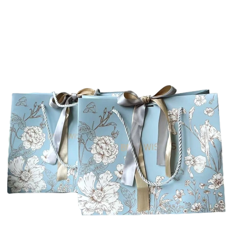 Special Craft Paper Bags feature soft light blue base fully printed with elegant sketch style white flowers leaves and butterfly patterns. White twisted rope handles are sturdy for daily carrying. Two tone satin bow in gold and silver ties on handle to add delicate romantic touch. Thick premium craft paper keeps the bag upright and maintains nice shape. Faint Best Wishes text is printed on surface to fit gift giving scenarios. We support custom bag size floral artwork bow style and brand logo. These paper bags fit wedding favors flower shop gifts birthday presents cosmetic packaging and holiday gift sets.