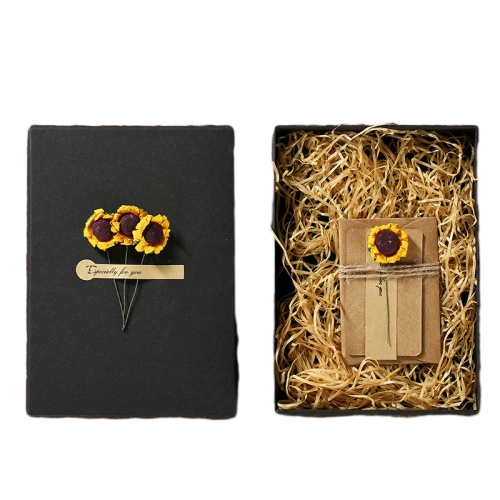 This square fliplid custom cardboard box features elegant matte black outer surface. Decorative artificial sunflower ornaments and paper label tags can be attached on the box lid to deliver warm festive atmosphere. The inner cavity can be filled with natural straw shred filler to cushion greeting cards small crafts and surprise gifts. Sturdy rigid cardboard structure keeps the box shape well during transportation. You can change outer color decorative flower styles label text and inner packing accessories. It fits well for holiday gifts handwritten card packages birthday presents souvenir sets and delicate handmade item packaging.